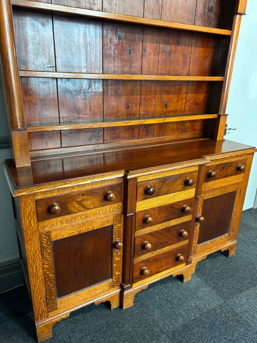 An antique oak Welsh dresser featuring an upper open plate rack with shelves and a lower breakfront base with central drawers flanked by cupboards. View III