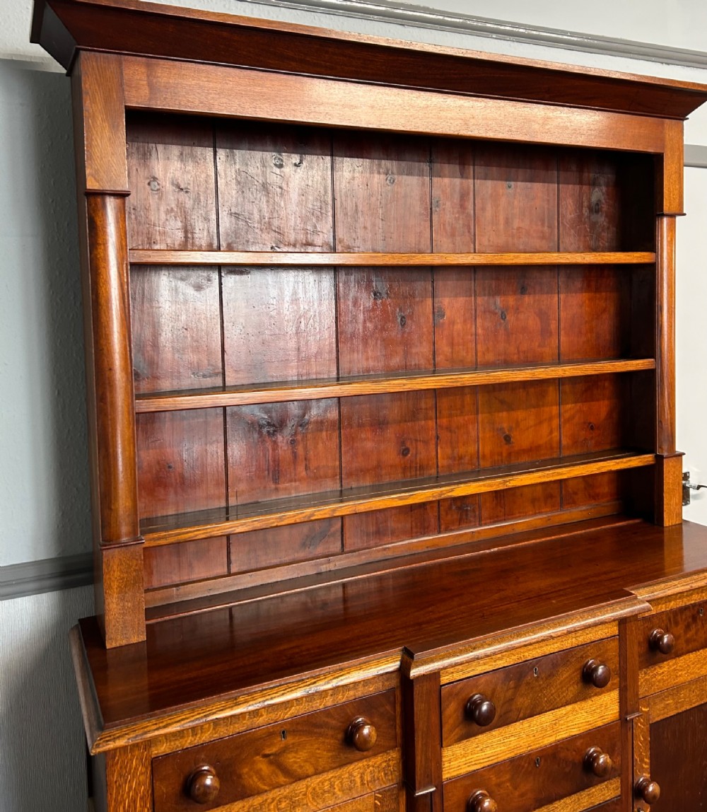 An antique oak Welsh dresser featuring an upper open plate rack with shelves and a lower breakfront base with central drawers flanked by cupboards. View IV