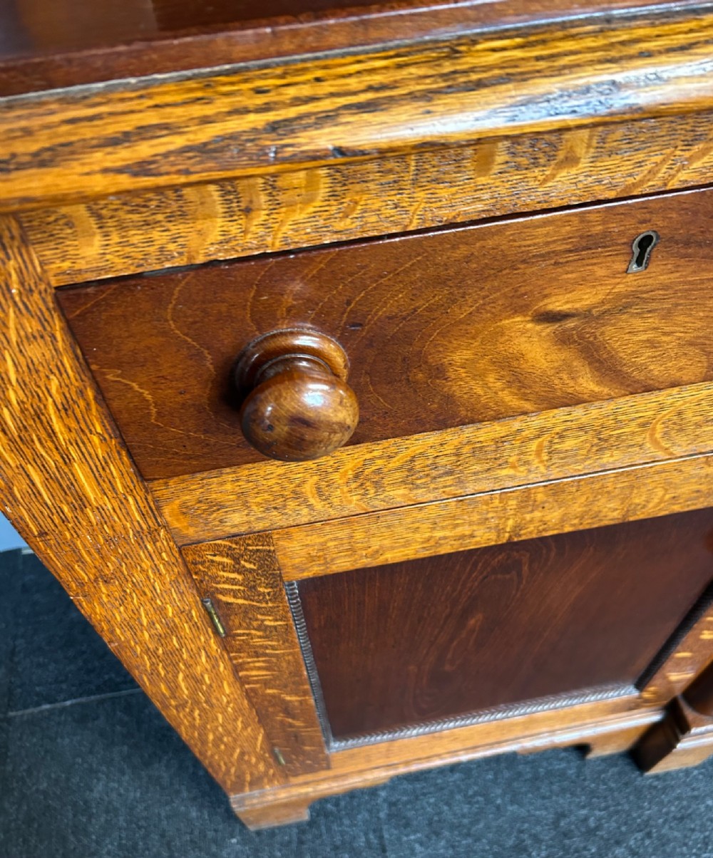 An antique oak Welsh dresser featuring an upper open plate rack with shelves and a lower breakfront base with central drawers flanked by cupboards. View V