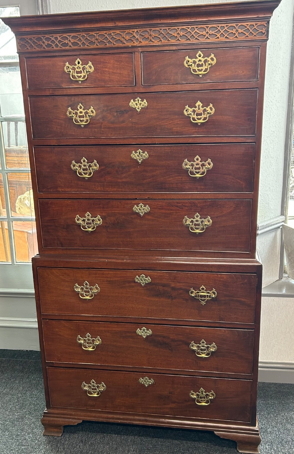 A tall Georgian mahogany chest on chest featuring eight drawers with brass swan-neck handles, blind fretwork frieze, and bracket feet. View II