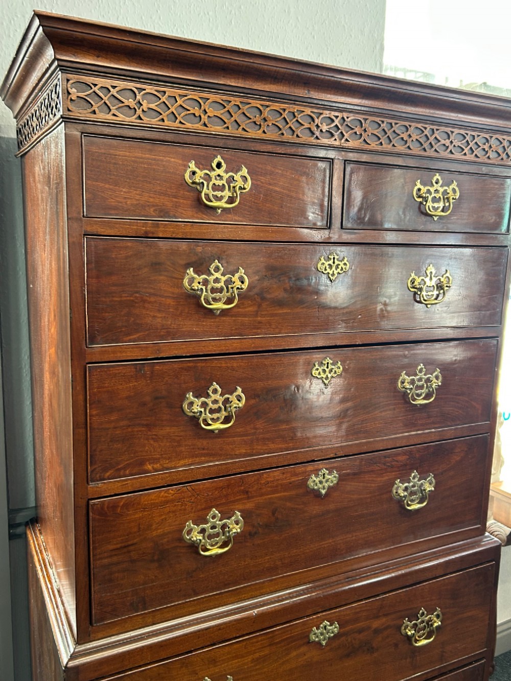 A tall Georgian mahogany chest on chest featuring eight drawers with brass swan-neck handles, blind fretwork frieze, and bracket feet. View V