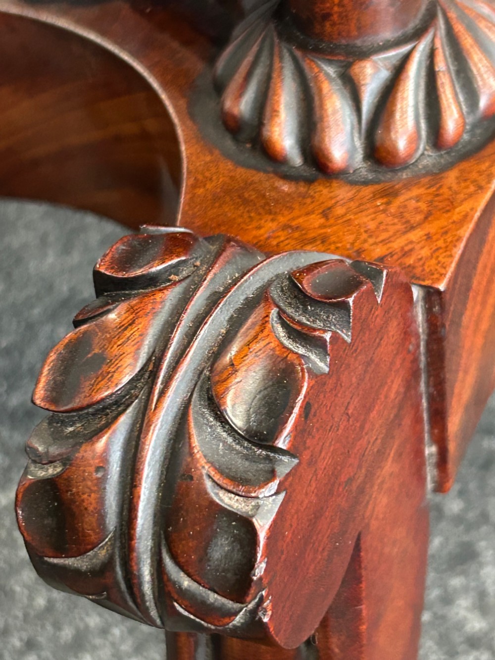 A William IV mahogany fold-over tea table with a flame mahogany top, central carved pedestal, and four splayed legs with brass paw castors. View VIII