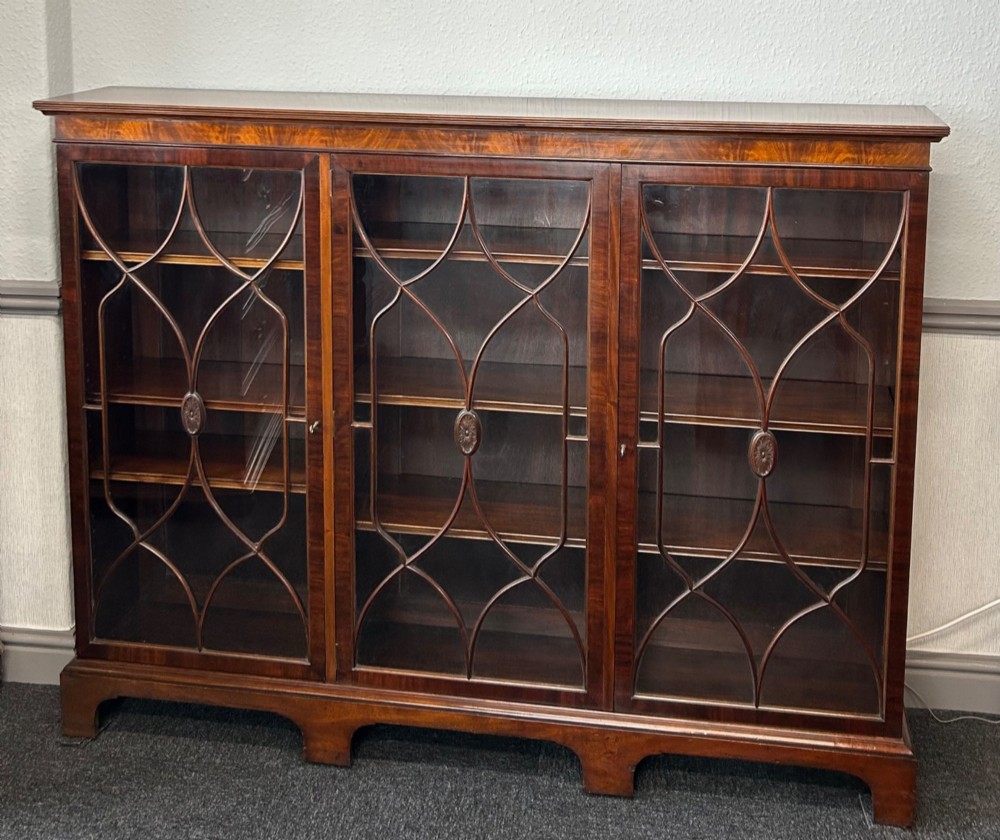 A large mahogany three-door glazed bookcase featuring geometric astragal glazing bars, carved oval motifs, and bracket feet. View II
