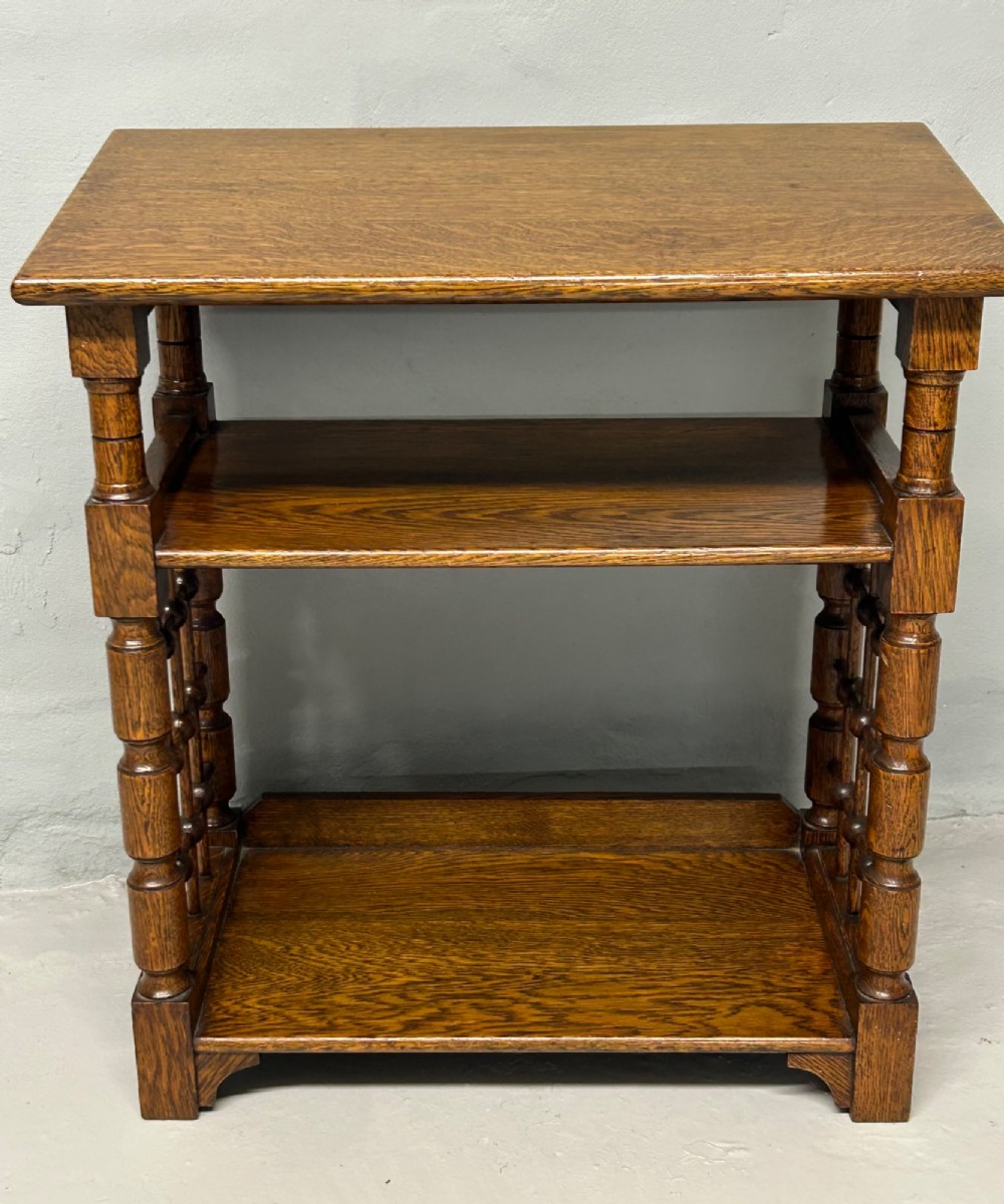 An antique warm brown oak book stand featuring a slanted top reading surface, two lower shelves, and turned spindle side galleries. View II