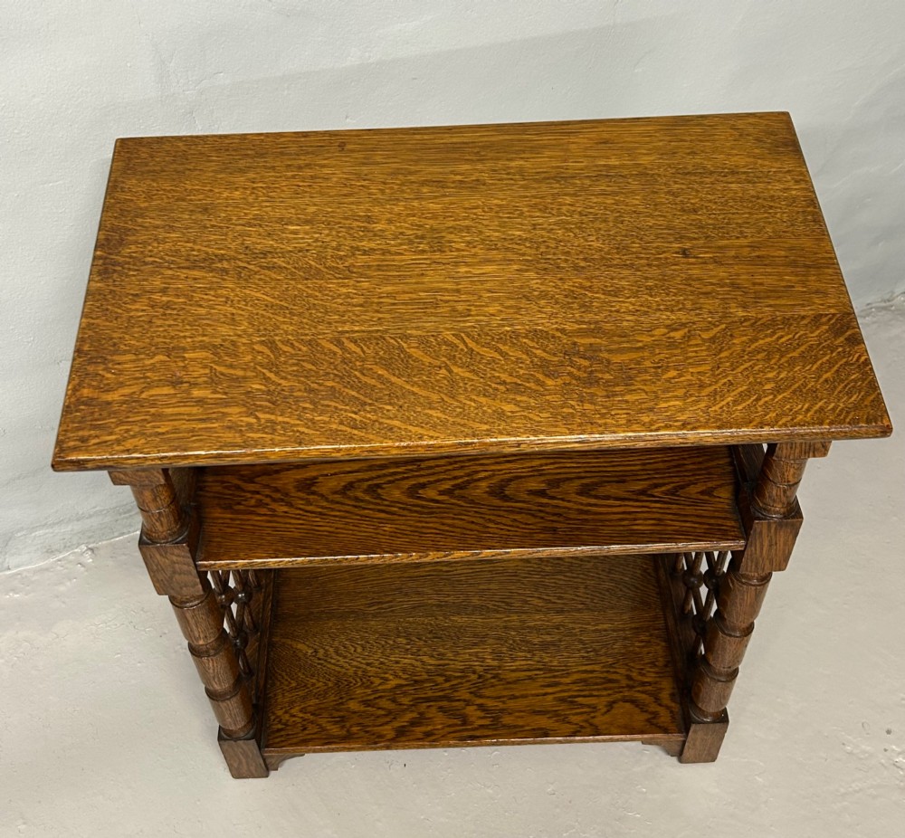 An antique warm brown oak book stand featuring a slanted top reading surface, two lower shelves, and turned spindle side galleries. View V