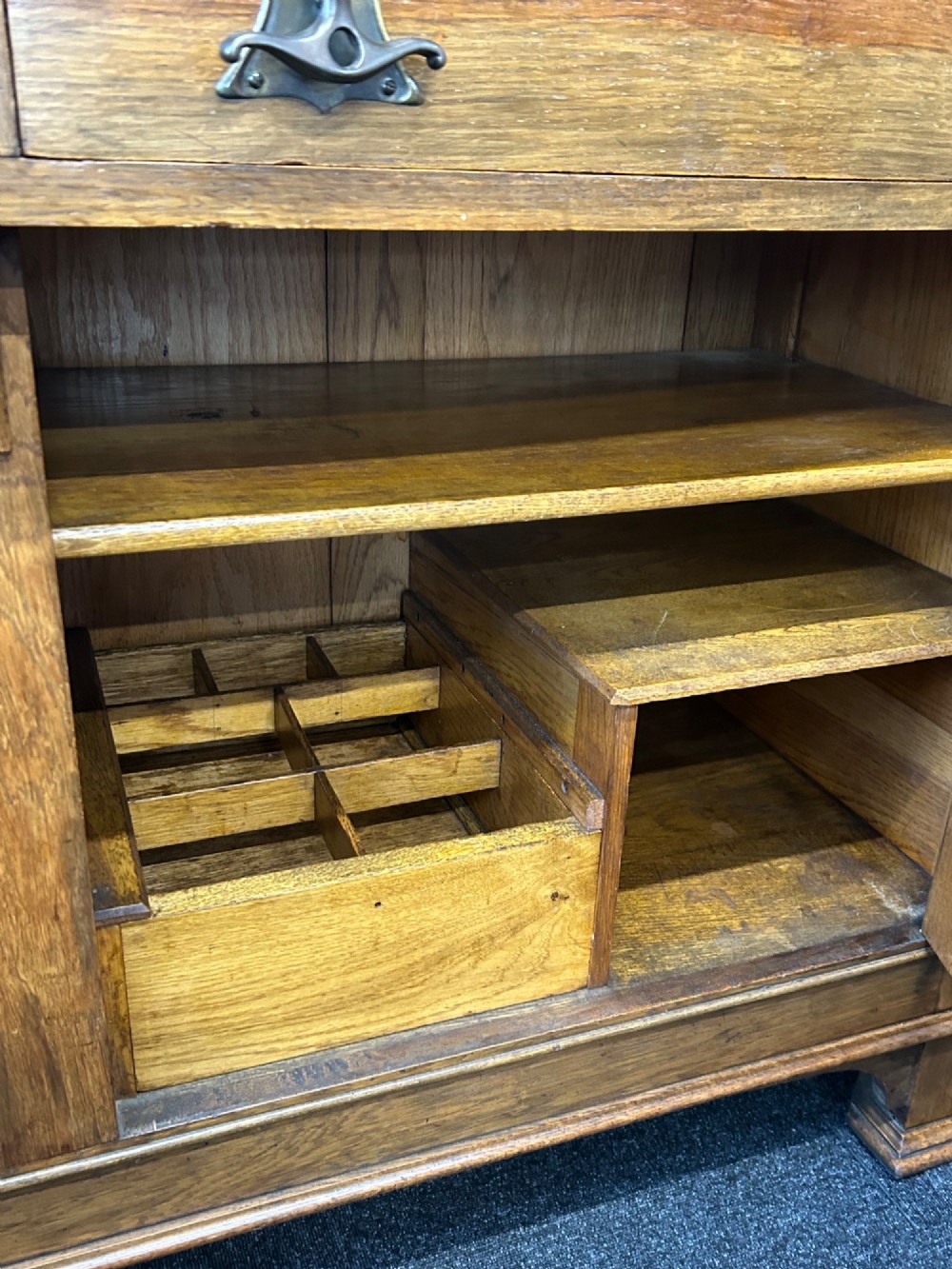 An Edwardian Arts and Crafts oak sideboard featuring a central mirrored superstructure flanked by bow-fronted leaded glass cabinets above drawers and carved panel doors. View VIII