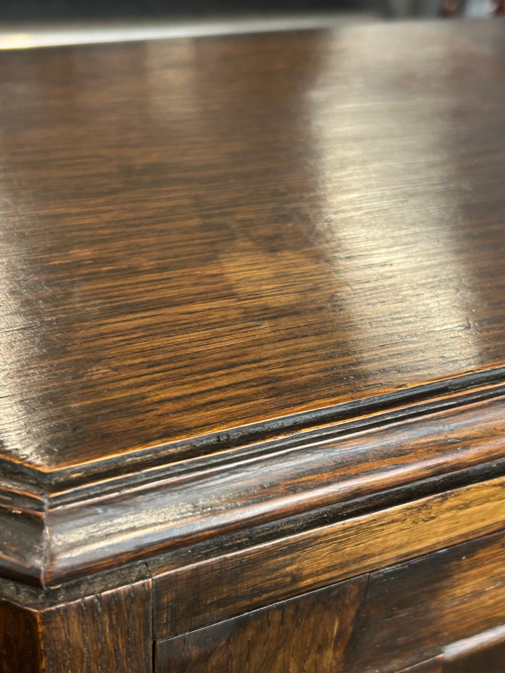 A medium brown oak cabinet featuring two glass-panelled doors, internal wooden shelves, a carved decorative apron, and turned legs with connecting stretchers. View VI