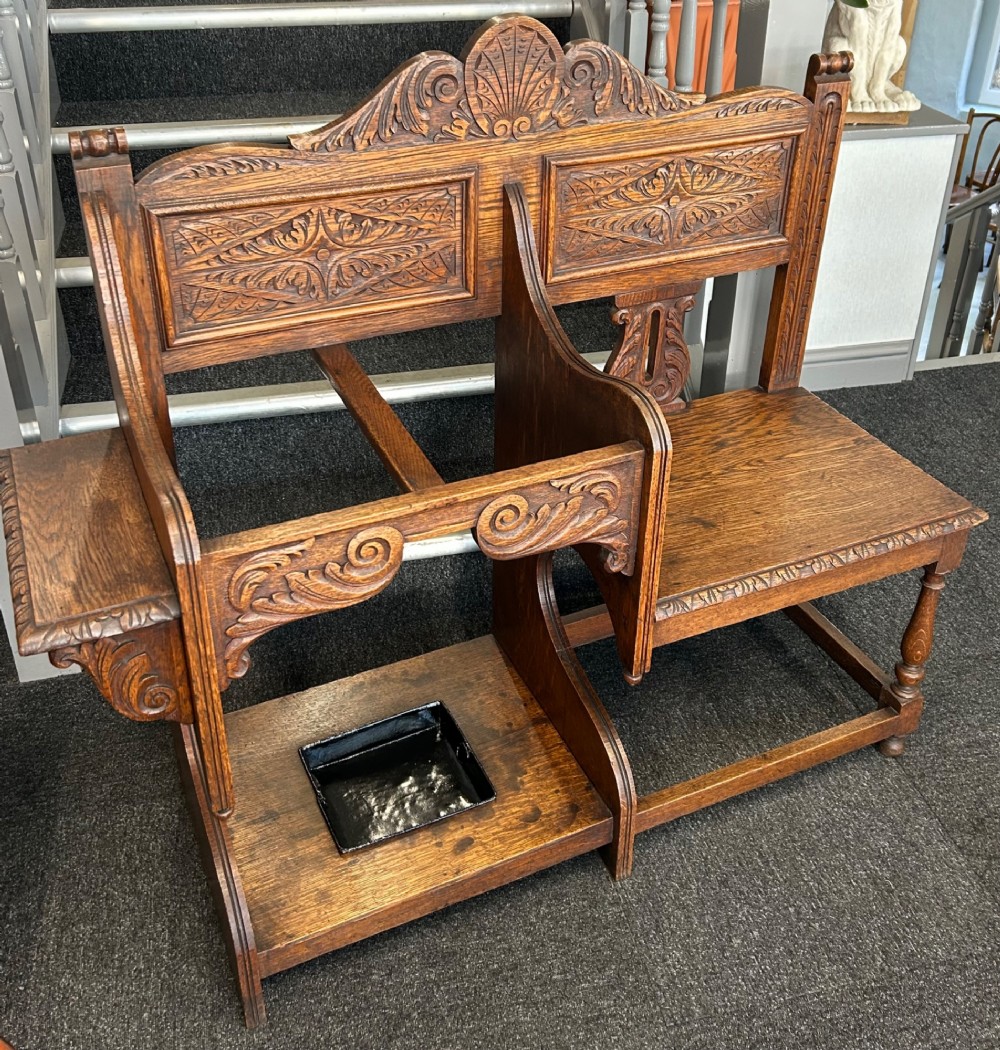 An antique carved oak hall seat featuring an integrated umbrella stand with drip tray, side shelf, and carved foliate back panels topped with a shell pediment. View III