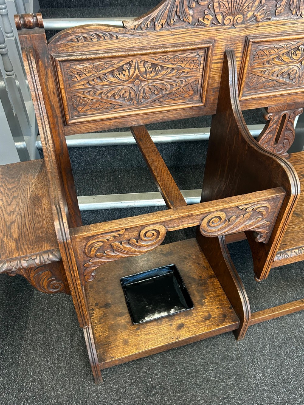 An antique carved oak hall seat featuring an integrated umbrella stand with drip tray, side shelf, and carved foliate back panels topped with a shell pediment. View IV