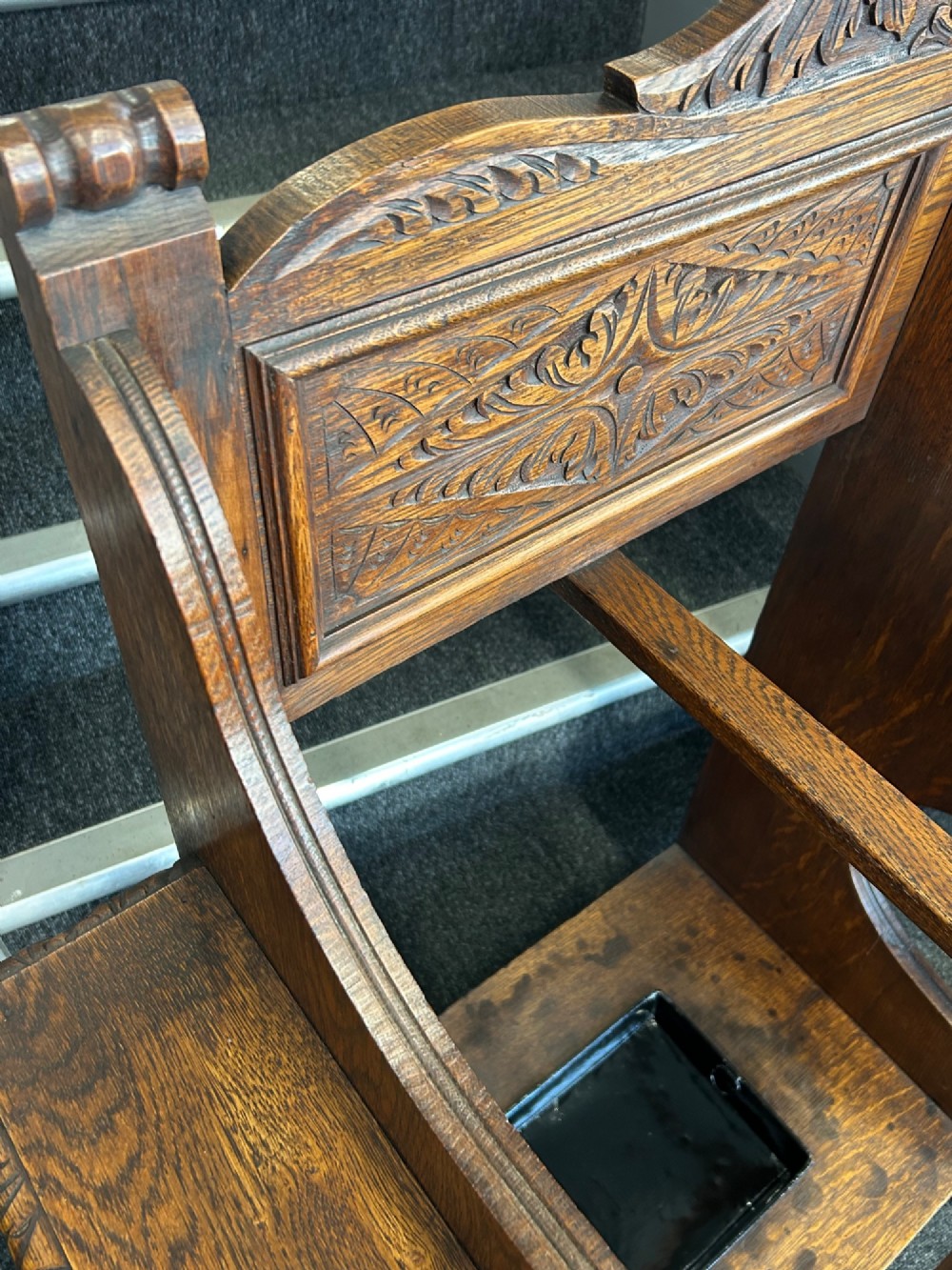 An antique carved oak hall seat featuring an integrated umbrella stand with drip tray, side shelf, and carved foliate back panels topped with a shell pediment. View VIII