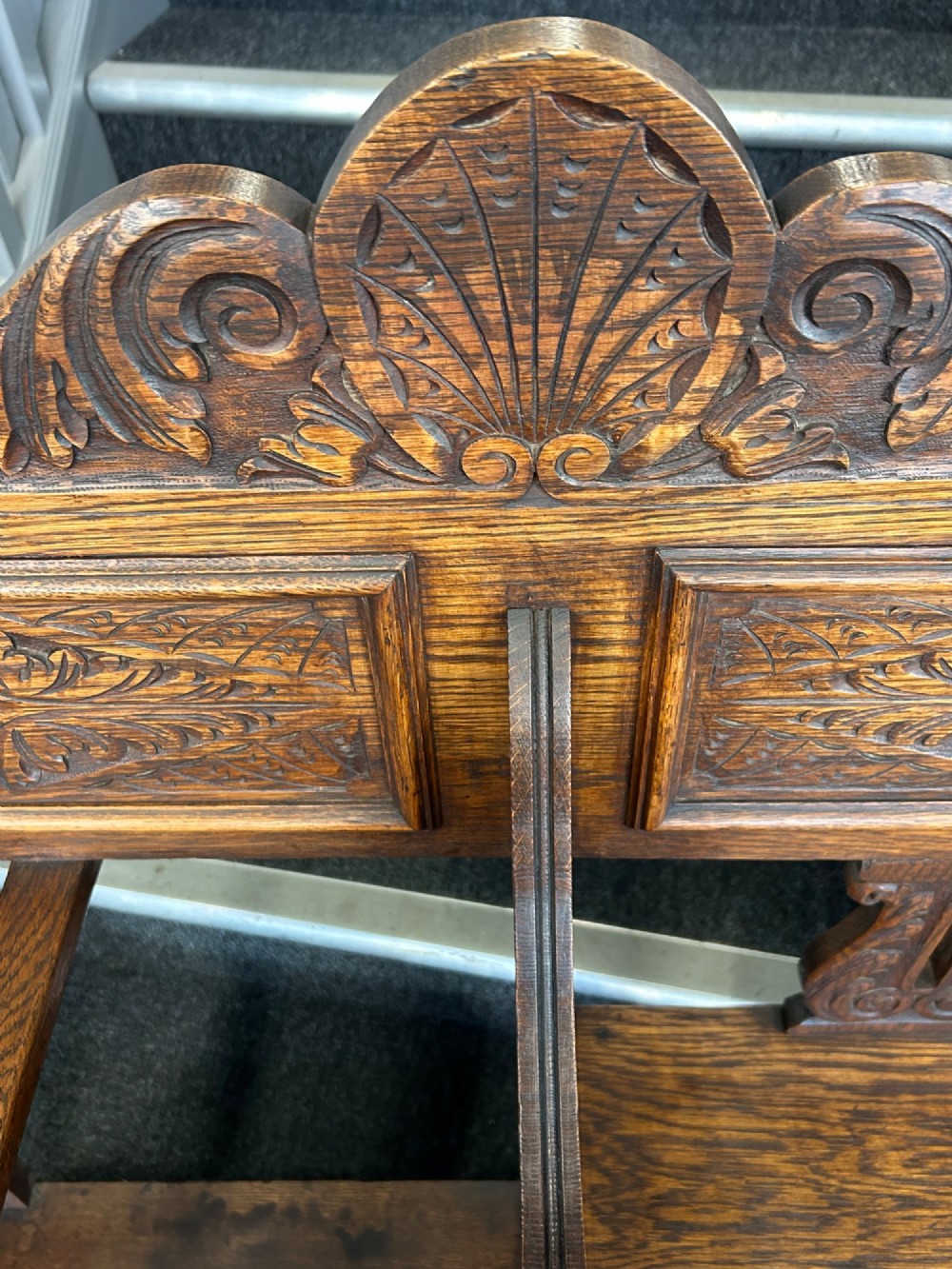 An antique carved oak hall seat featuring an integrated umbrella stand with drip tray, side shelf, and carved foliate back panels topped with a shell pediment. View IX