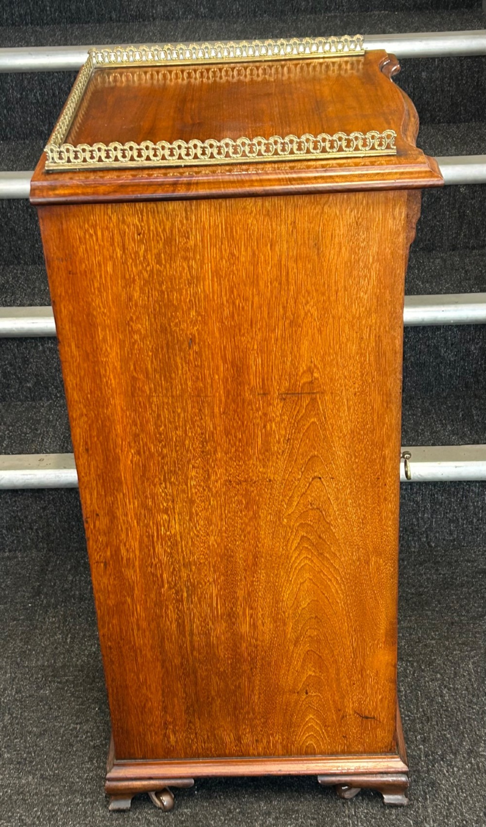 An Edwardian walnut music cabinet featuring a brass gallery top rail, a single glazed door, and lined interior shelves with small brass labels. View II