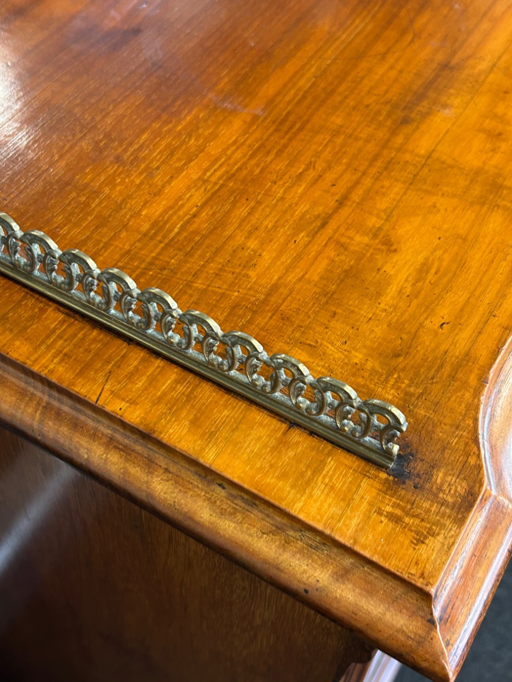 An Edwardian walnut music cabinet featuring a brass gallery top rail, a single glazed door, and lined interior shelves with small brass labels. View VI