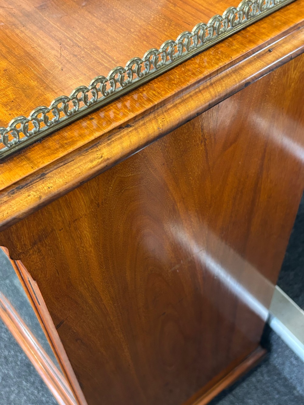 An Edwardian walnut music cabinet featuring a brass gallery top rail, a single glazed door, and lined interior shelves with small brass labels. View VII