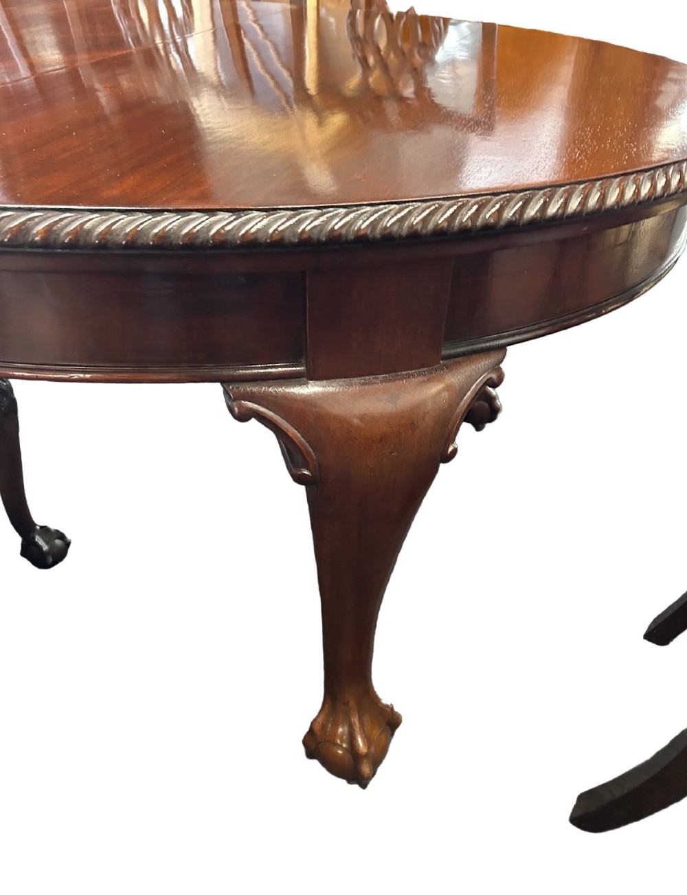 An extending mahogany dining table featuring a carved rope edge and cabriole legs, surrounded by eight Chippendale style chairs with pierced back splats. View IV