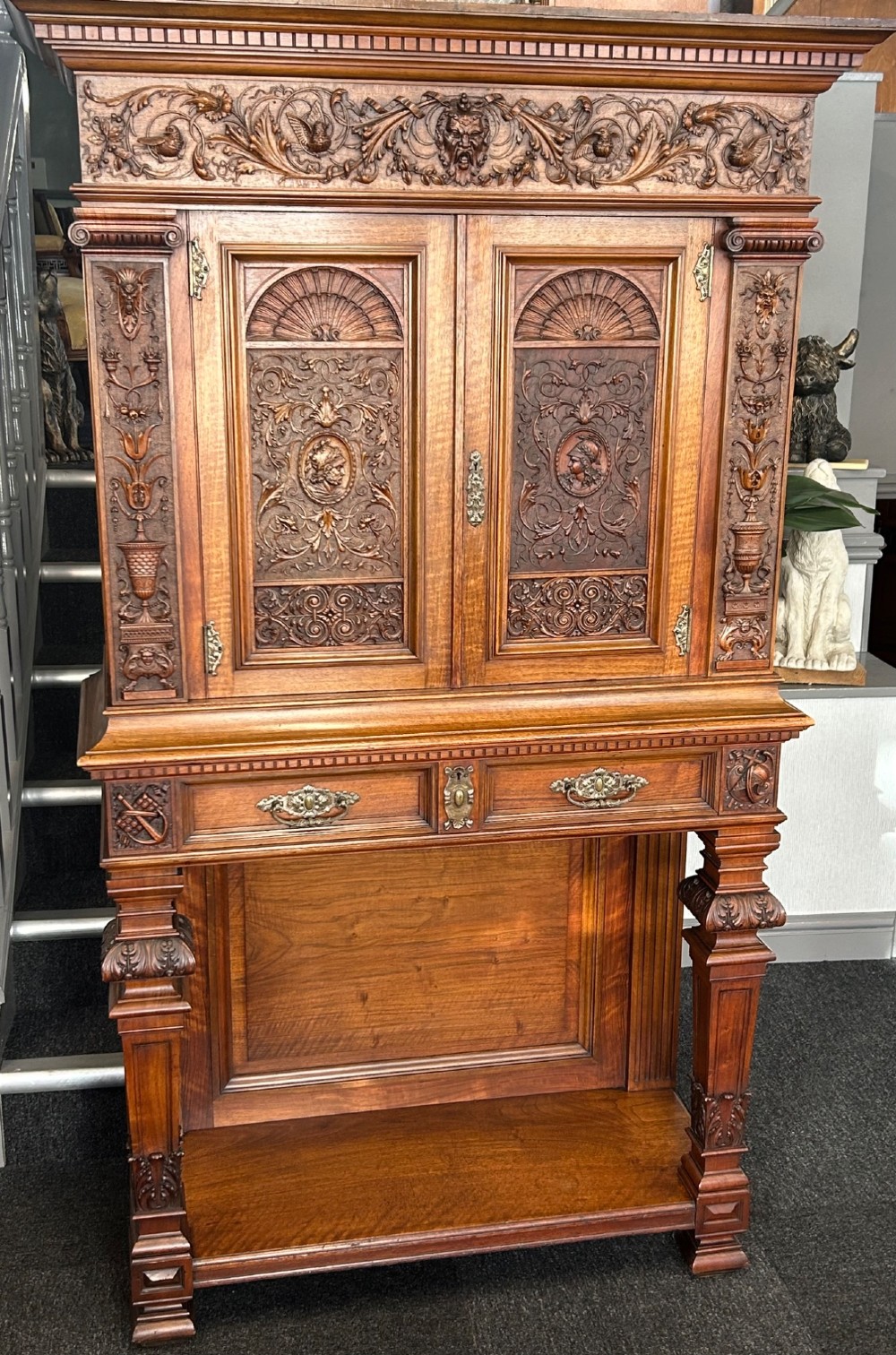 A 19th-century Renaissance Revival carved wood cabinet-on-stand with intricate relief carvings, twin doors, upper drawers, and an open lower shelf. View II