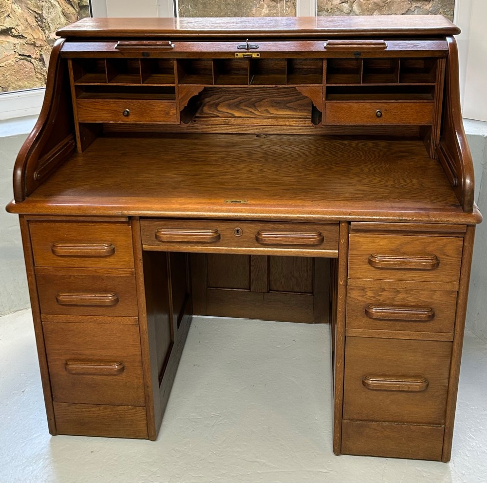 A warm brown oak roll top desk featuring a tambour slatted shutter top, central drawers, and twin pedestals with integrated storage drawers. View II