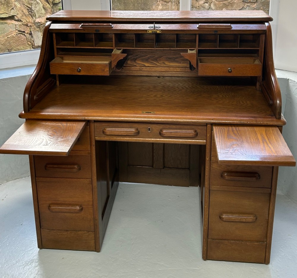 A warm brown oak roll top desk featuring a tambour slatted shutter top, central drawers, and twin pedestals with integrated storage drawers. View V