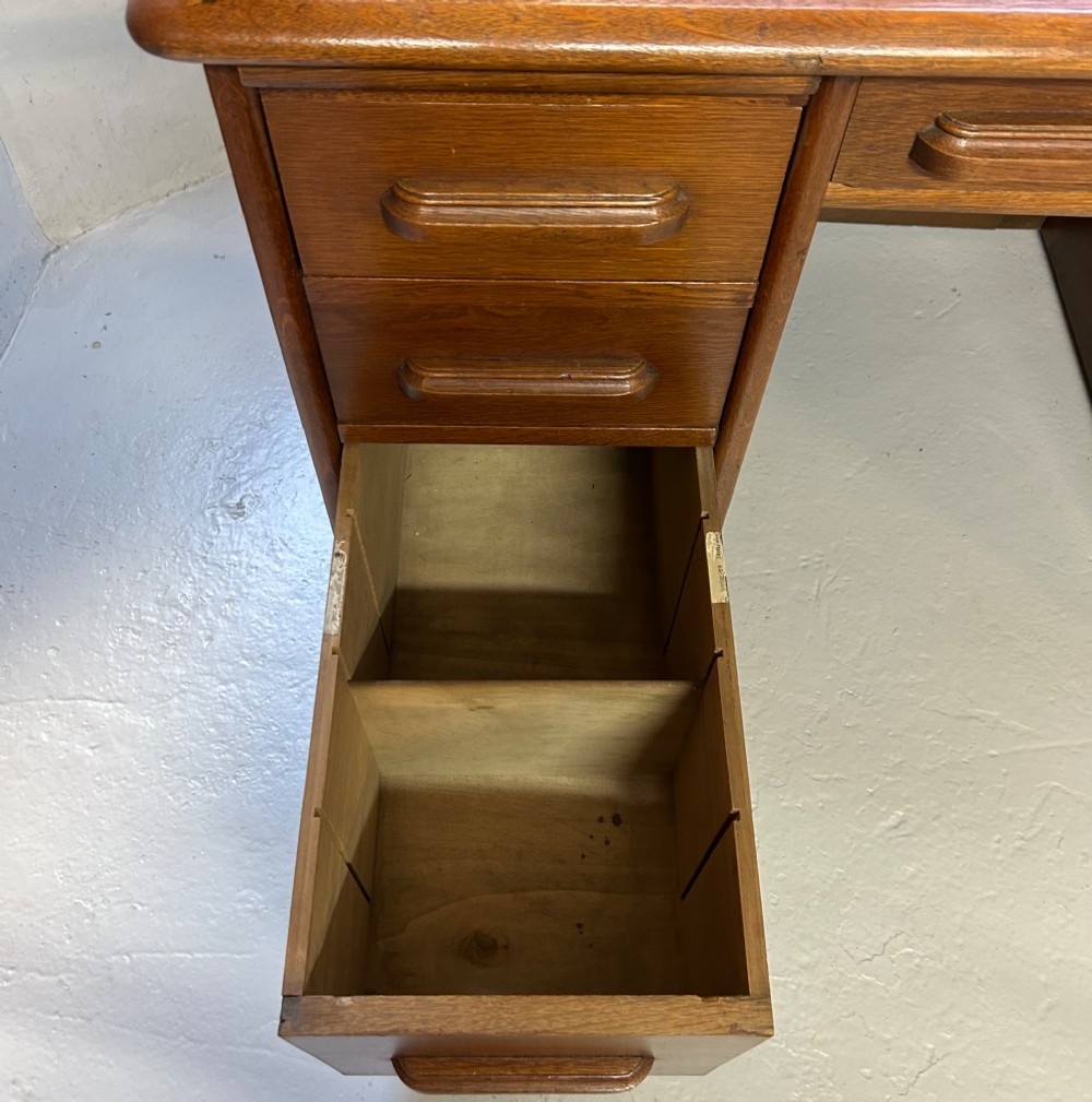 A warm brown oak roll top desk featuring a tambour slatted shutter top, central drawers, and twin pedestals with integrated storage drawers. View XIII