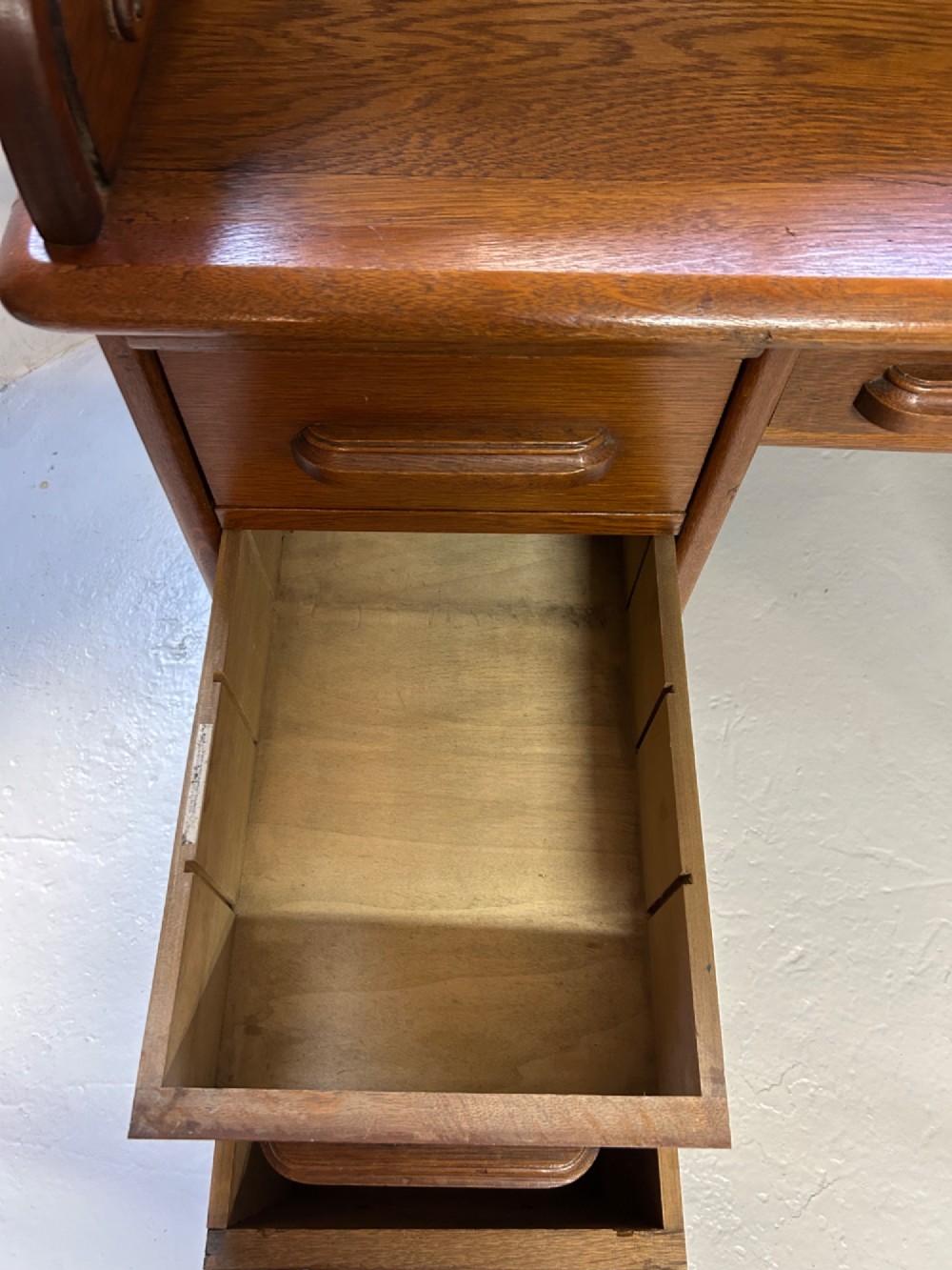 A warm brown oak roll top desk featuring a tambour slatted shutter top, central drawers, and twin pedestals with integrated storage drawers. View XIV