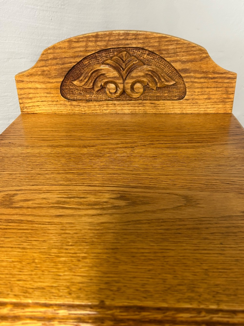 A matching pair of light oak bedside cabinets featuring carved crest galleries, single drawers, single panel doors, and brass fittings. View V