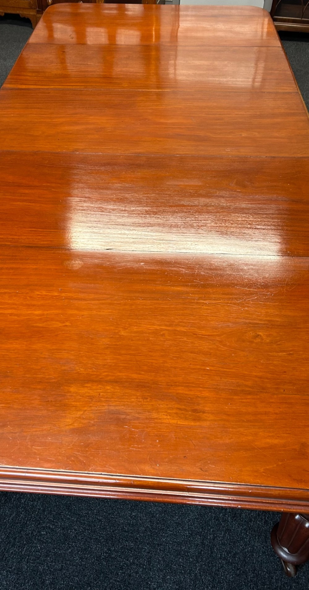 A Victorian mahogany extending dining table featuring three insertion leaves, rounded corners, polished finish, and reeded turned legs on brass castors. View IV