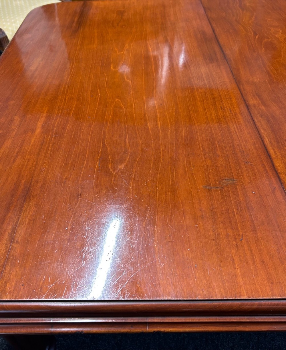 A Victorian mahogany extending dining table featuring three insertion leaves, rounded corners, polished finish, and reeded turned legs on brass castors. View V