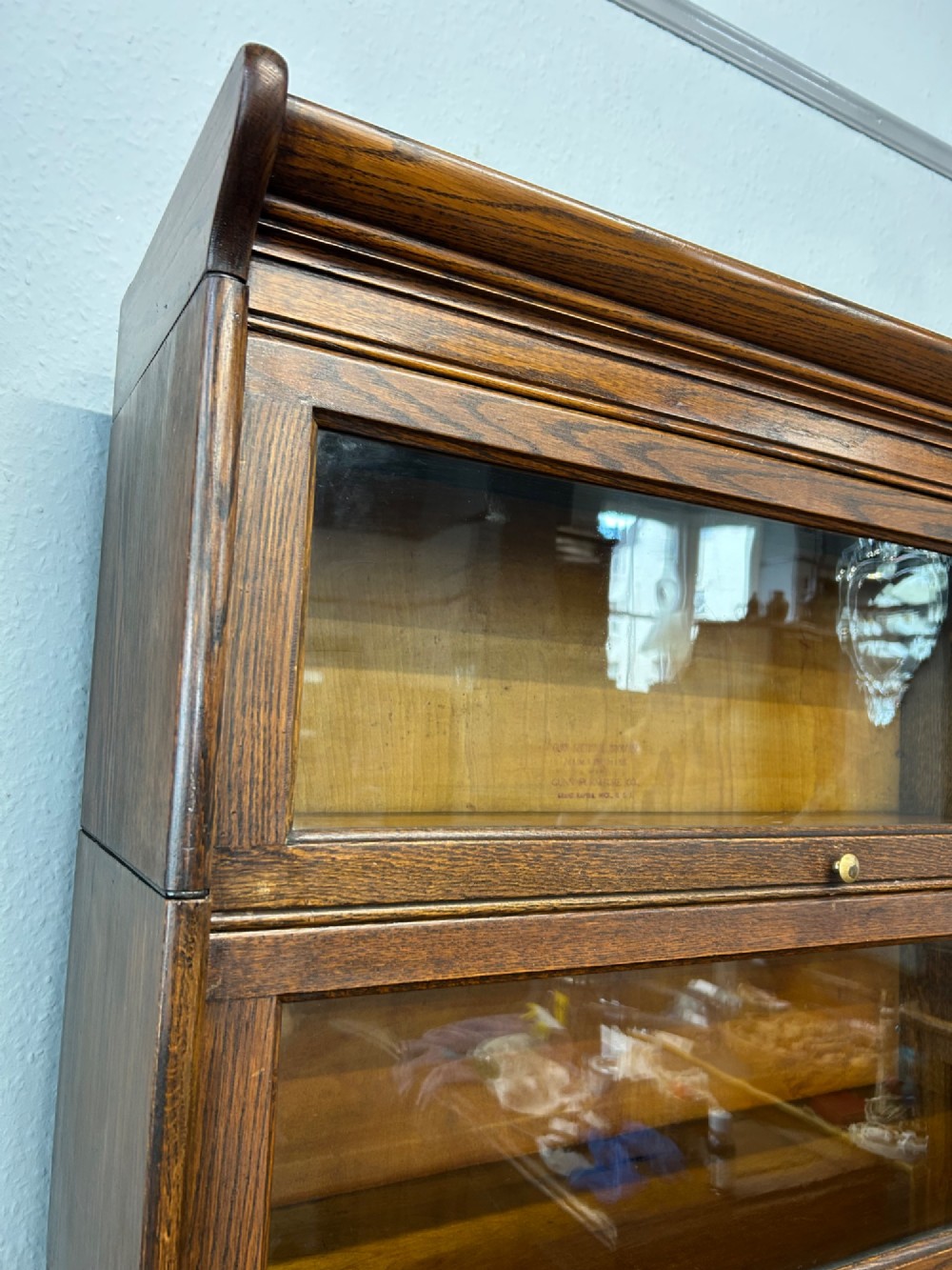 A five-tier oak barrister bookcase with glazed up-and-over doors and small brass knobs. View IV