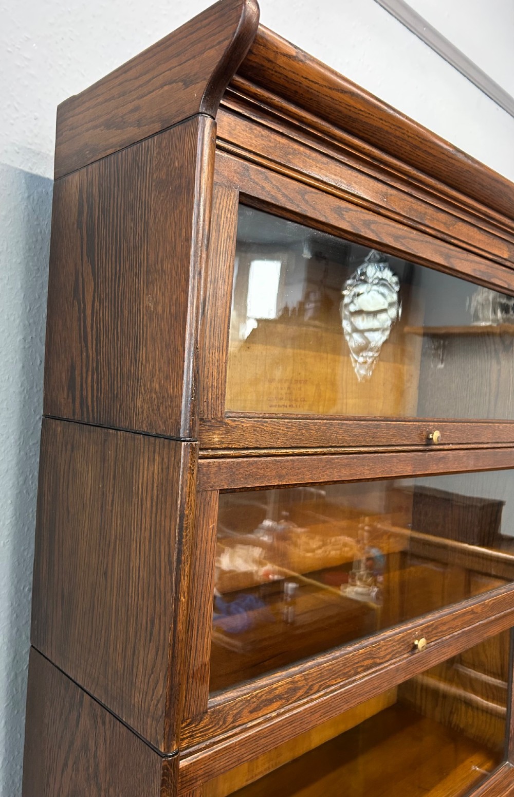 A five-tier oak barrister bookcase with glazed up-and-over doors and small brass knobs. View V