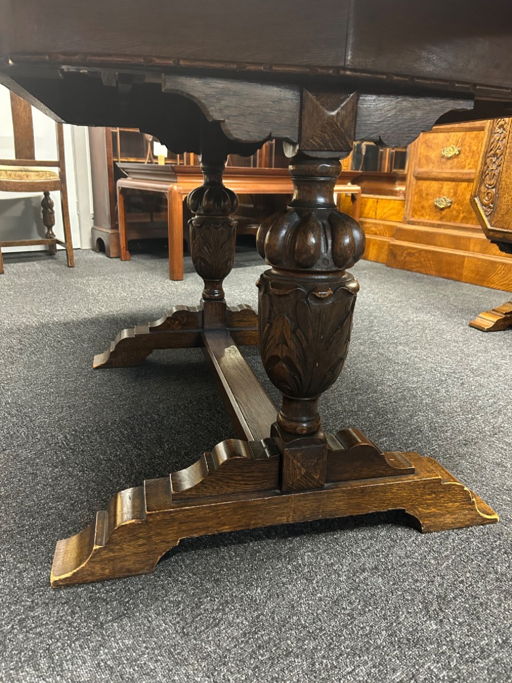 An Art Deco dark oak dining table featuring carved legs paired with four matching chairs with patterned upholstered seats. View IV