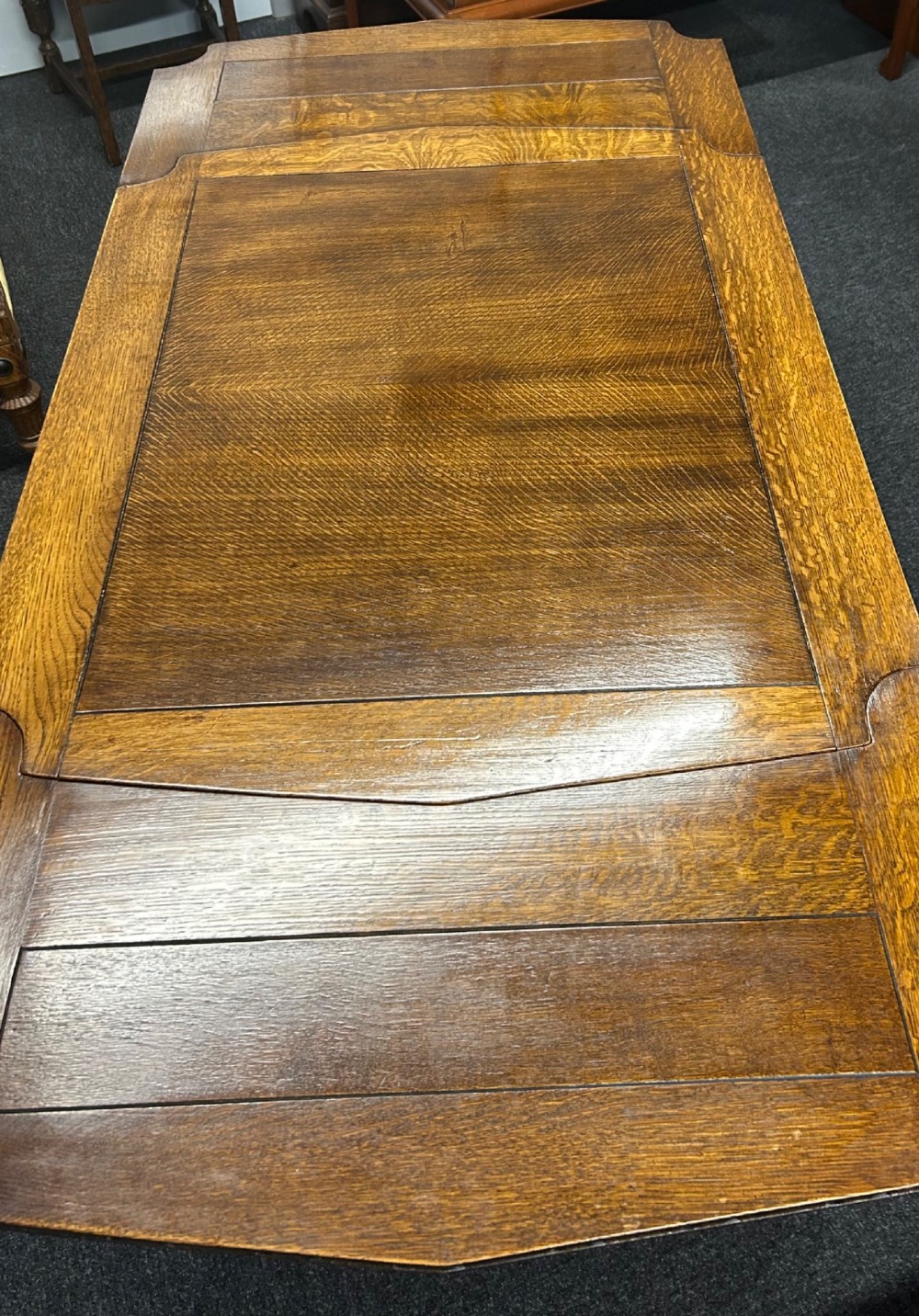 An Art Deco dark oak dining table featuring carved legs paired with four matching chairs with patterned upholstered seats. View V