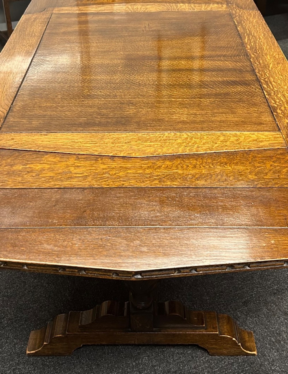 An Art Deco dark oak dining table featuring carved legs paired with four matching chairs with patterned upholstered seats. View VI
