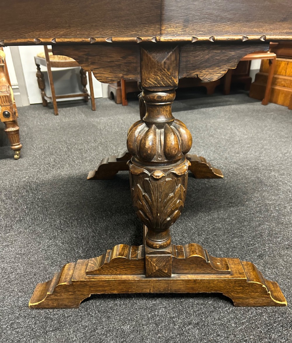 An Art Deco dark oak dining table featuring carved legs paired with four matching chairs with patterned upholstered seats. View IX