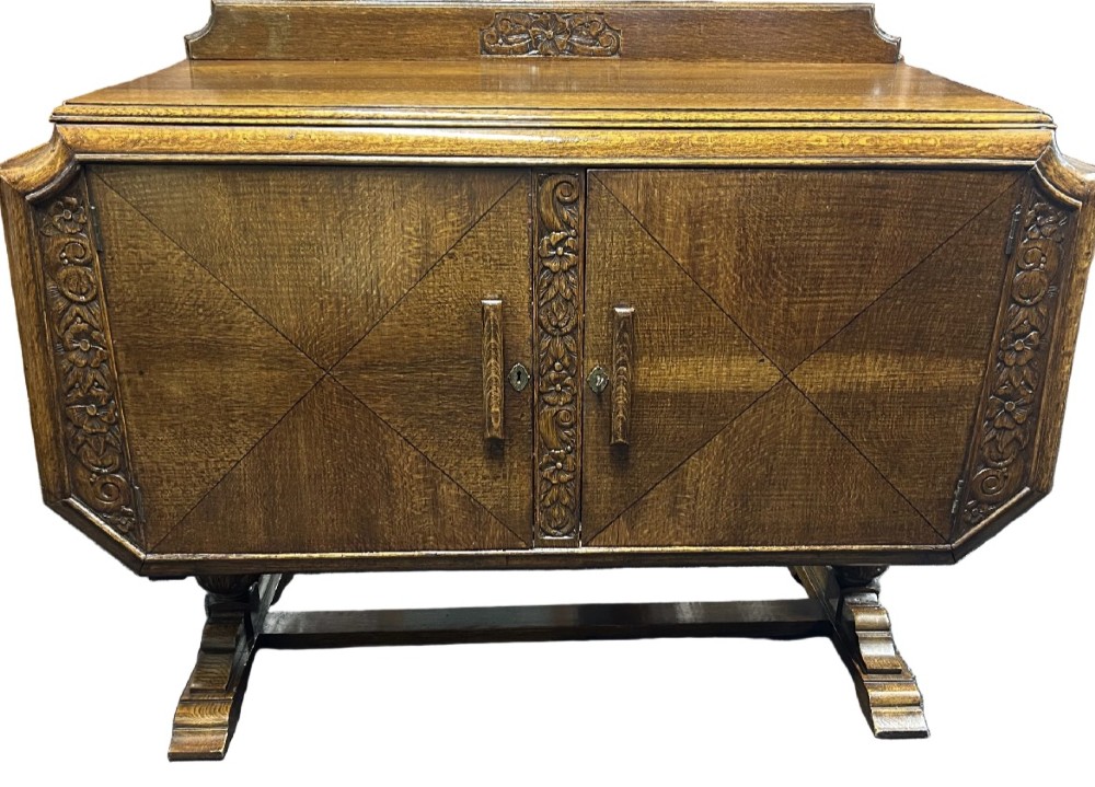 An Art Deco dark oak sideboard featuring diamond-pattern veneered double doors, carved floral borders, wooden handles, and a low upstand gallery. View II
