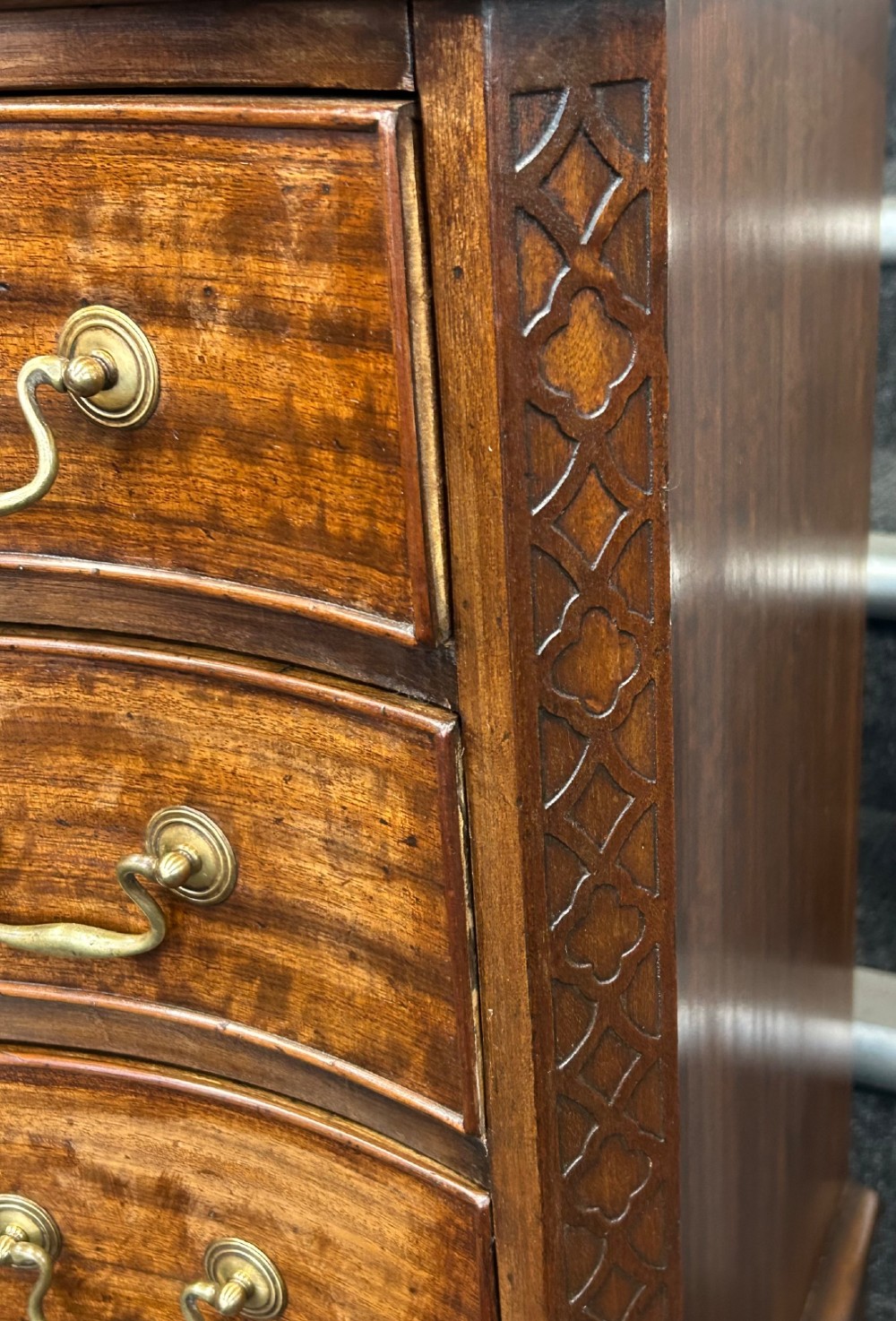 A Georgian Revival mahogany chest of drawers featuring a serpentine front, four graduated drawers with brass handles, blind fretwork on canted corners, and bracket feet. View III