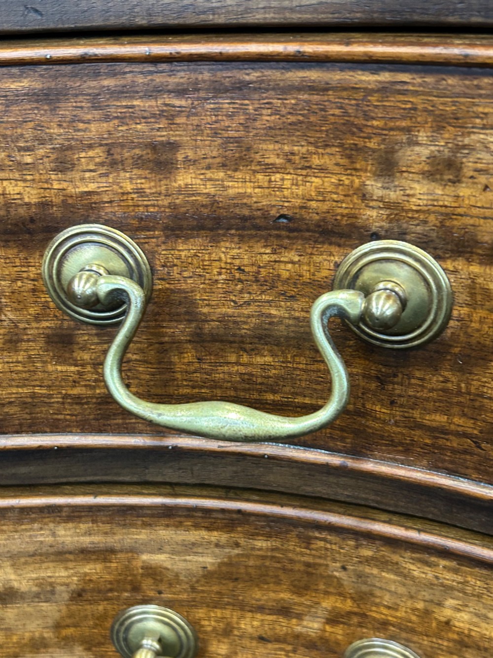 A Georgian Revival mahogany chest of drawers featuring a serpentine front, four graduated drawers with brass handles, blind fretwork on canted corners, and bracket feet. View IV