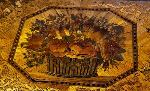 fig 1. An antique rectangular wooden box embellished with straw marquetry forming a central floral basket surrounded by intricate decorative borders in golden yellow and brown shades.