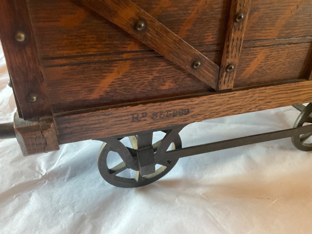 An antique Victorian oak cigar humidor constructed in the shape of a railway coal wagon with metal wheels, side bracing, and faux coal lining the top. View III