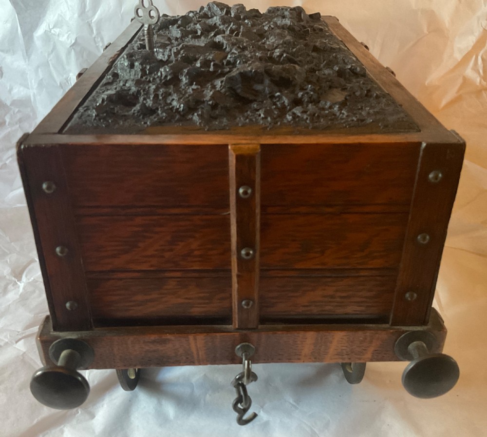 An antique Victorian oak cigar humidor constructed in the shape of a railway coal wagon with metal wheels, side bracing, and faux coal lining the top. View VII