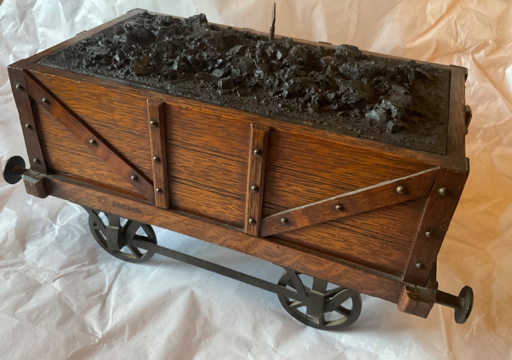 An antique Victorian oak cigar humidor constructed in the shape of a railway coal wagon with metal wheels, side bracing, and faux coal lining the top. View VIII