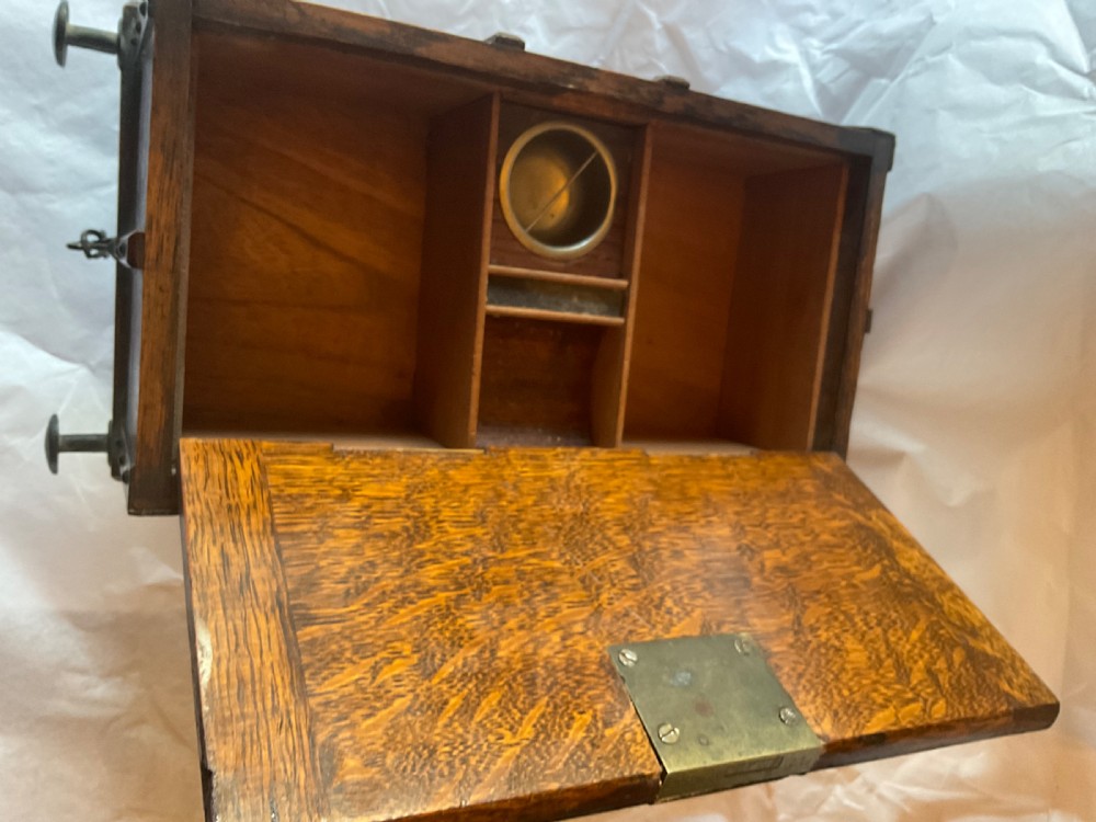 An antique Victorian oak cigar humidor constructed in the shape of a railway coal wagon with metal wheels, side bracing, and faux coal lining the top. View X