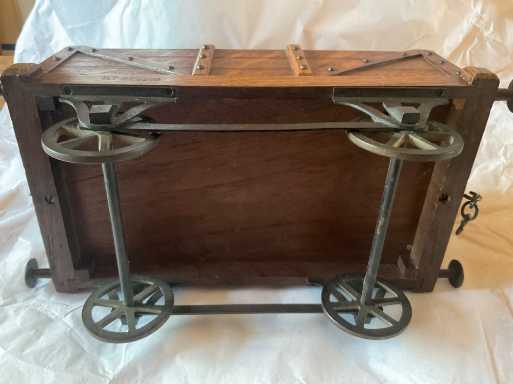 An antique Victorian oak cigar humidor constructed in the shape of a railway coal wagon with metal wheels, side bracing, and faux coal lining the top. View XII