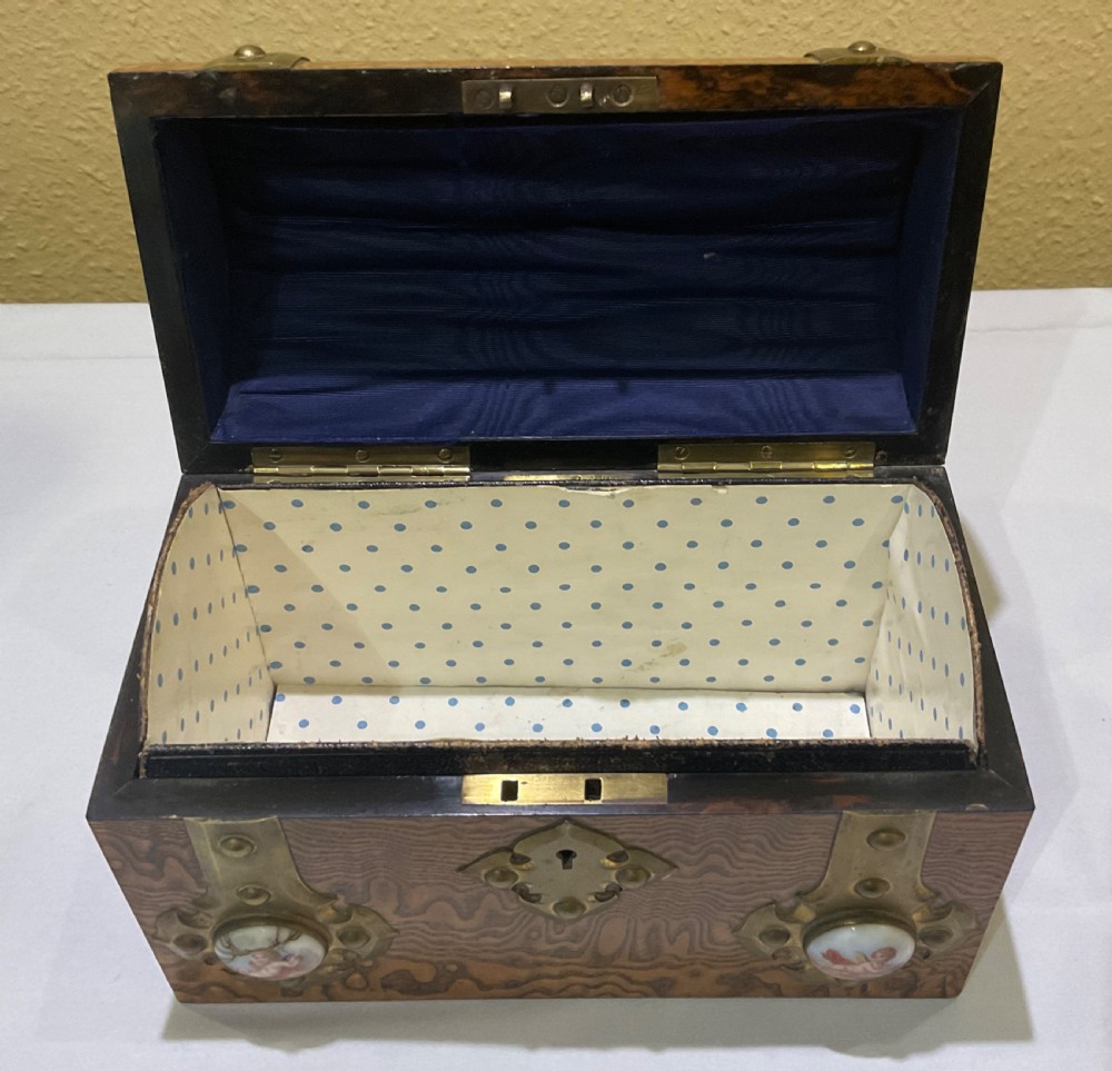 A Victorian domed walnut casket featuring brass strapwork, decorative studs, keyhole escutcheon, and porcelain cabochons with painted cherubs. View II