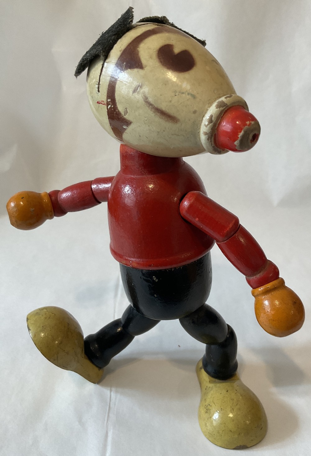 A vintage jointed wooden figure painted in red, black, yellow, and cream, styled as a cartoon character with felt ears. View V