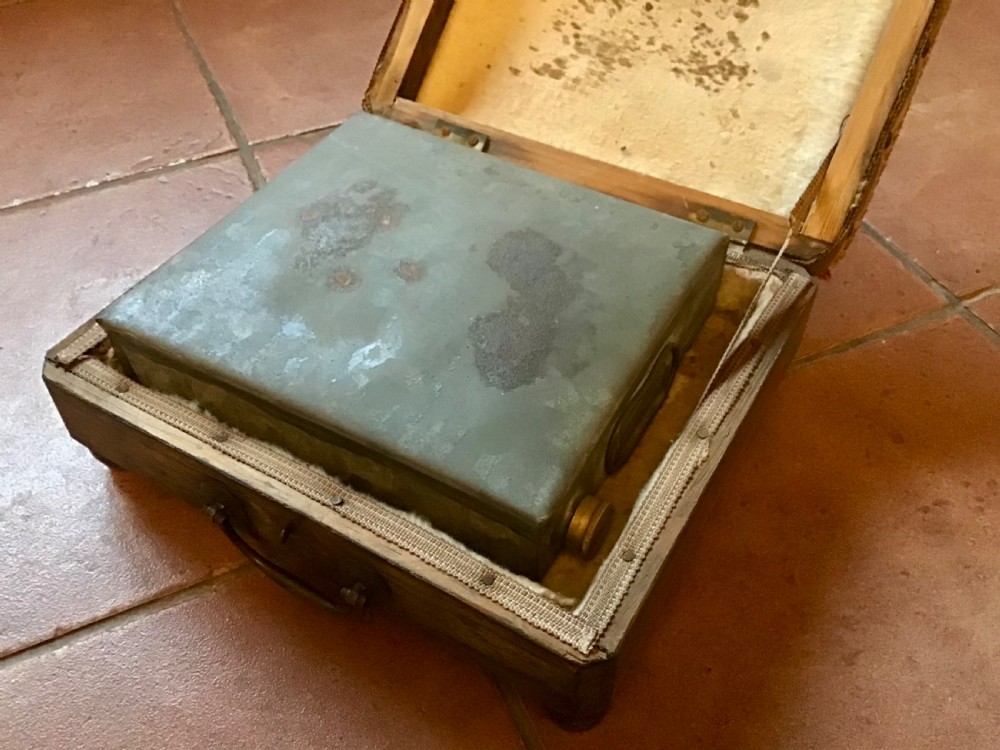 An antique Victorian carriage foot warmer featuring a square patterned carpet top with stud detailing, a wooden base with turned feet, and a metal carry handle. View II