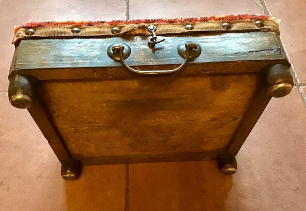 An antique Victorian carriage foot warmer featuring a square patterned carpet top with stud detailing, a wooden base with turned feet, and a metal carry handle. View V