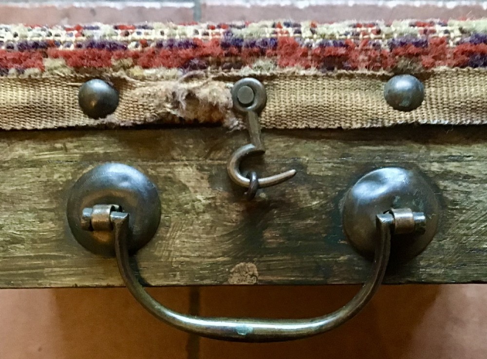 An antique Victorian carriage foot warmer featuring a square patterned carpet top with stud detailing, a wooden base with turned feet, and a metal carry handle. View VIII