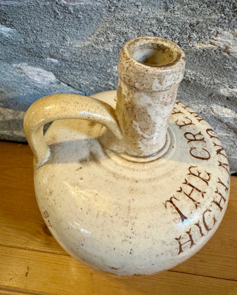 A cream glazed Victorian stoneware whisky jug featuring brown transfer-printed typography and botanical decoration with a single side handle. View V