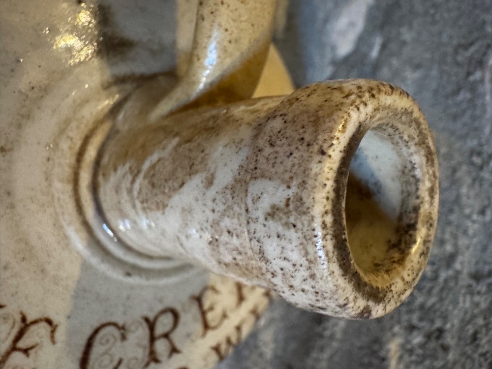A cream glazed Victorian stoneware whisky jug featuring brown transfer-printed typography and botanical decoration with a single side handle. View IX