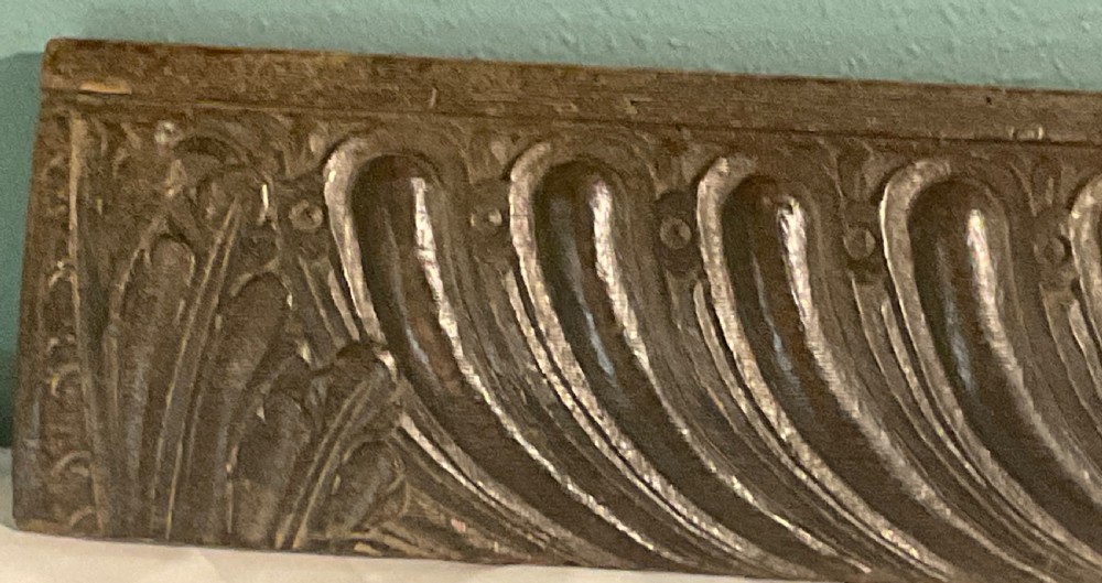 A long rectangular 17th-century carved dark oak frieze panel with repeating diagonal fluting and leaf end motifs. View III
